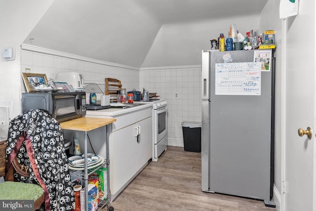 kitchen with white electric range, vaulted ceiling, light hardwood / wood-style flooring, fridge, and tile walls