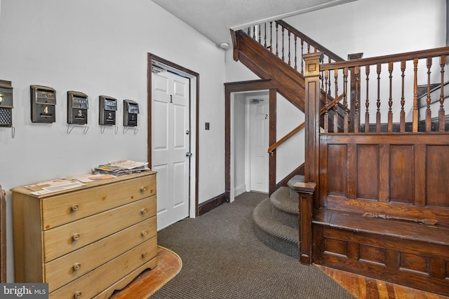 staircase featuring dark colored carpet