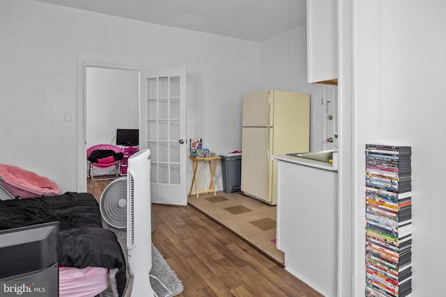 bedroom with white fridge, french doors, and dark hardwood / wood-style flooring