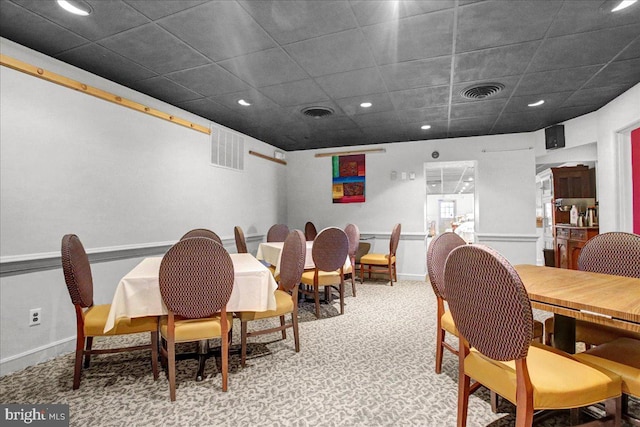 dining space featuring light carpet and a paneled ceiling