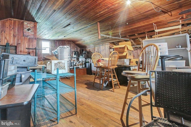 dining area featuring wooden walls, lofted ceiling, and light hardwood / wood-style flooring