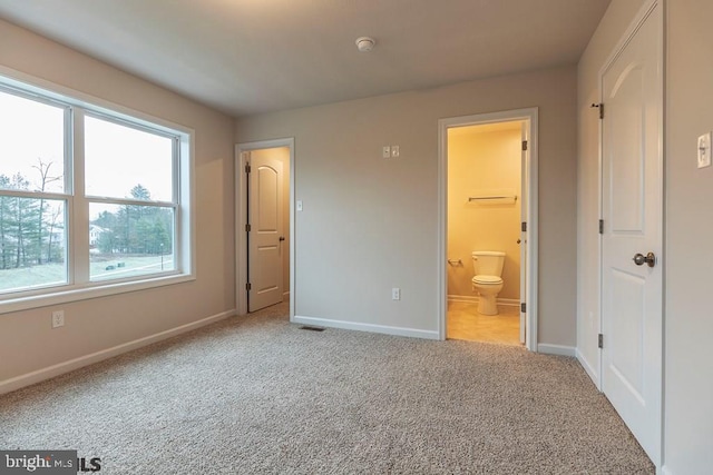 unfurnished bedroom featuring connected bathroom and light colored carpet