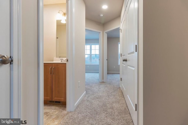 corridor featuring light carpet and sink