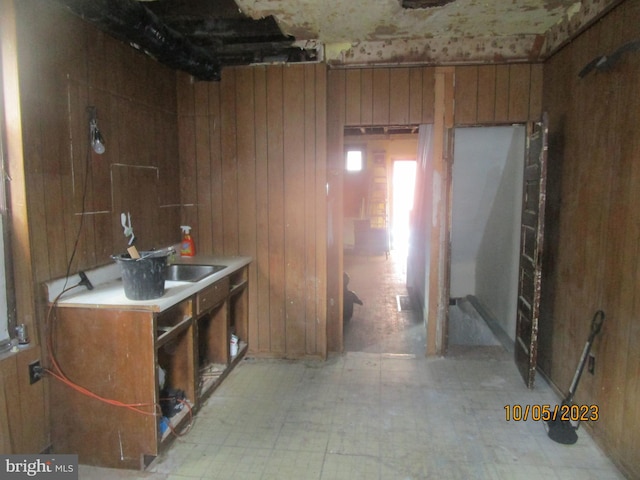 interior space with wood walls, light tile floors, and sink