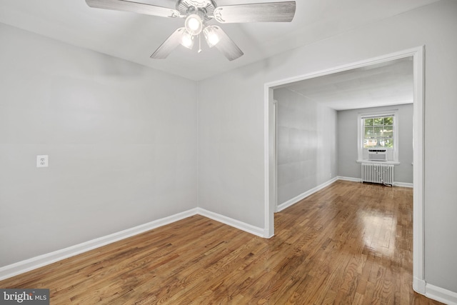 spare room featuring ceiling fan, radiator heating unit, and wood-type flooring