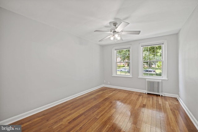 unfurnished room with ceiling fan, hardwood / wood-style flooring, and radiator