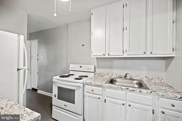 kitchen with white cabinetry, white appliances, dark tile floors, sink, and light stone counters