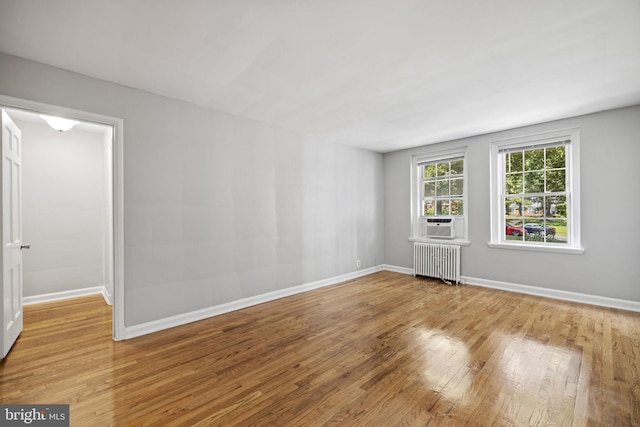 unfurnished room with radiator heating unit and light wood-type flooring