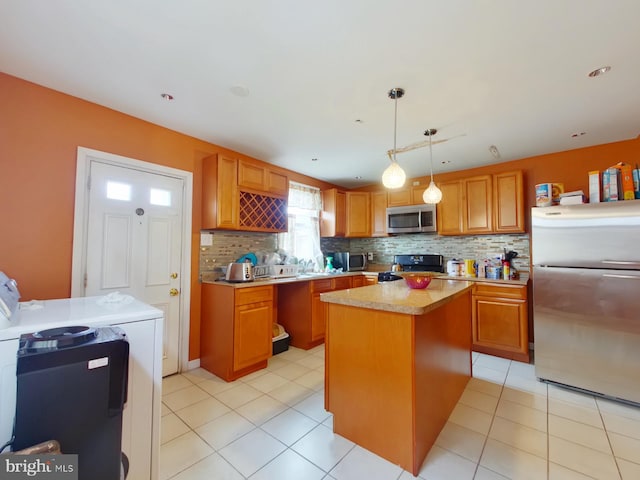 kitchen featuring a kitchen island, tasteful backsplash, stainless steel appliances, washer / clothes dryer, and pendant lighting