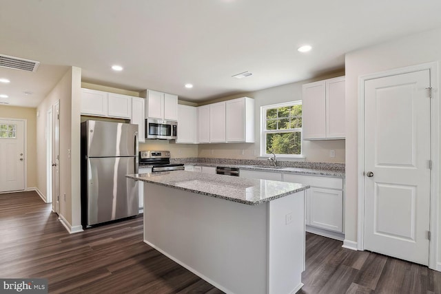 kitchen featuring sink, a kitchen island, stainless steel appliances, light stone countertops, and white cabinets