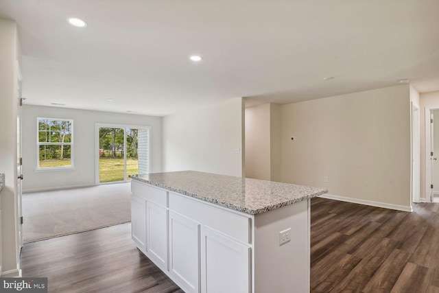 kitchen with a kitchen island, dark hardwood / wood-style floors, white cabinets, and light stone counters