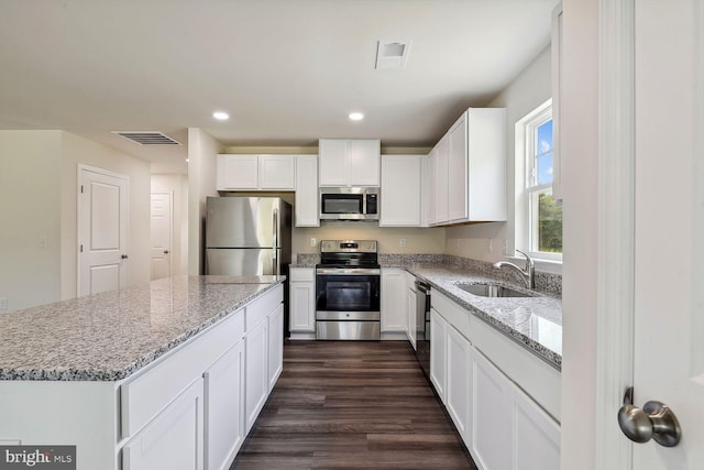 kitchen featuring stainless steel appliances, light stone countertops, sink, and white cabinets