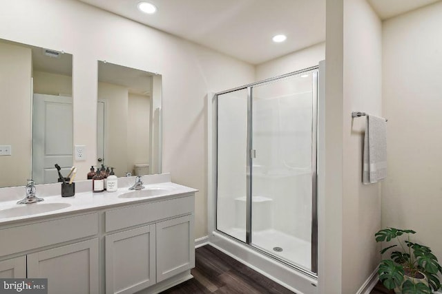 bathroom featuring vanity, hardwood / wood-style flooring, a shower with door, and toilet