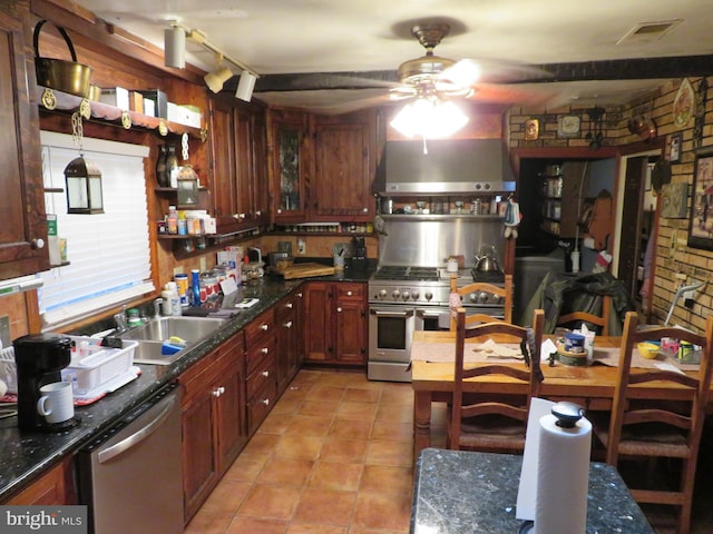 kitchen with appliances with stainless steel finishes, wall chimney range hood, ceiling fan, light tile floors, and sink