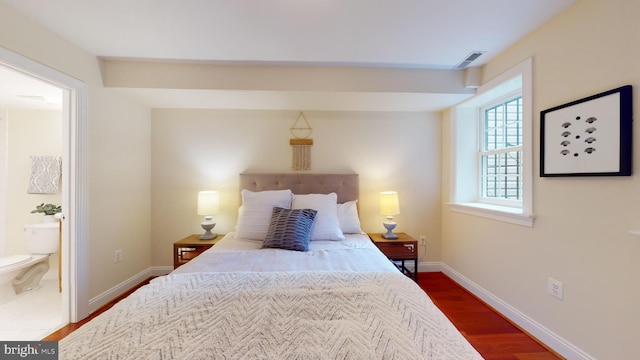 bedroom with ensuite bath and dark hardwood / wood-style floors