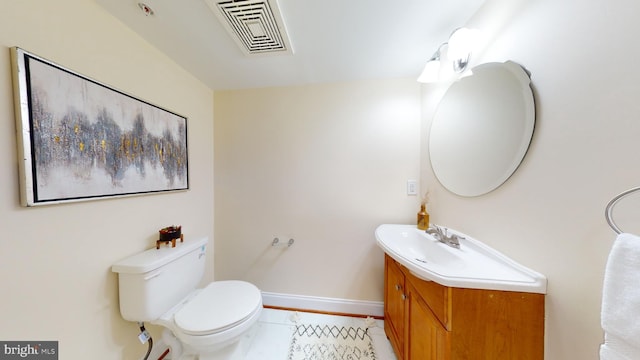 bathroom with toilet, vanity, and tile flooring