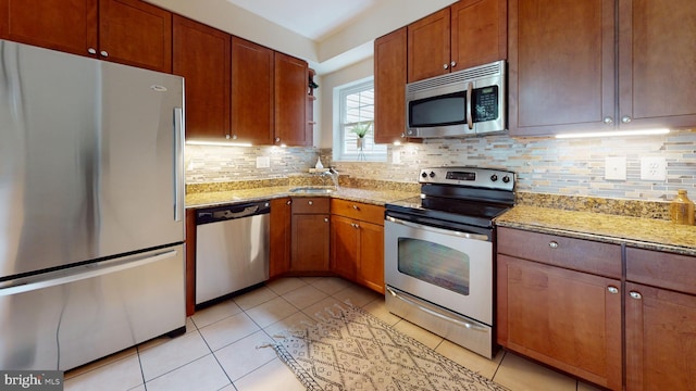 kitchen featuring light tile flooring, tasteful backsplash, stainless steel appliances, and light stone countertops