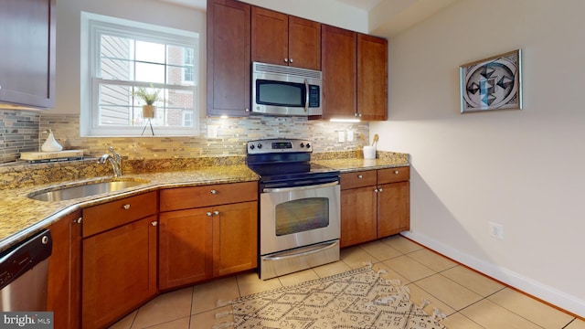 kitchen featuring appliances with stainless steel finishes, tasteful backsplash, light stone countertops, and sink