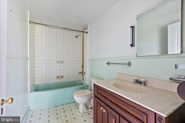 full bathroom with tiled shower / bath, toilet, large vanity, and tile floors