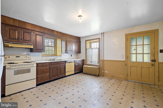 kitchen featuring white appliances, light tile flooring, radiator heating unit, and a wealth of natural light