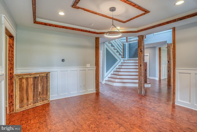 spare room with decorative columns, dark hardwood / wood-style floors, and a tray ceiling