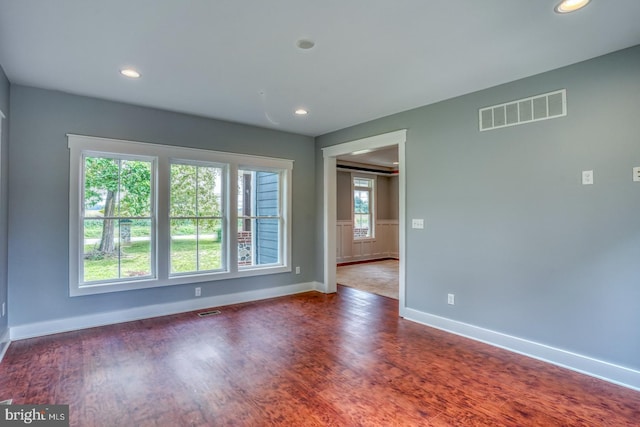 empty room with dark hardwood / wood-style flooring and a wealth of natural light