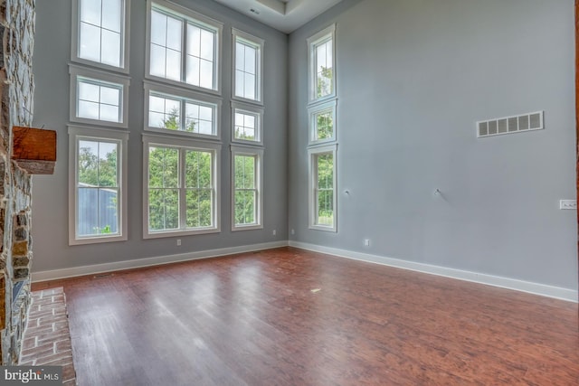 unfurnished living room with dark hardwood / wood-style flooring, a fireplace, and a high ceiling