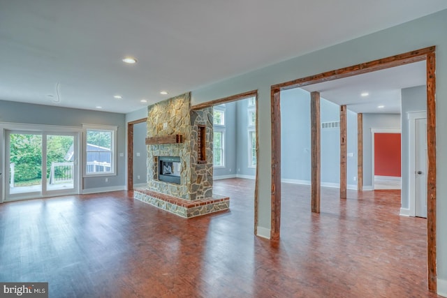 unfurnished living room featuring wood-type flooring and a stone fireplace