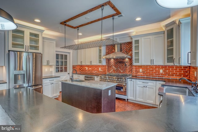 kitchen featuring wall chimney range hood, backsplash, appliances with stainless steel finishes, and pendant lighting