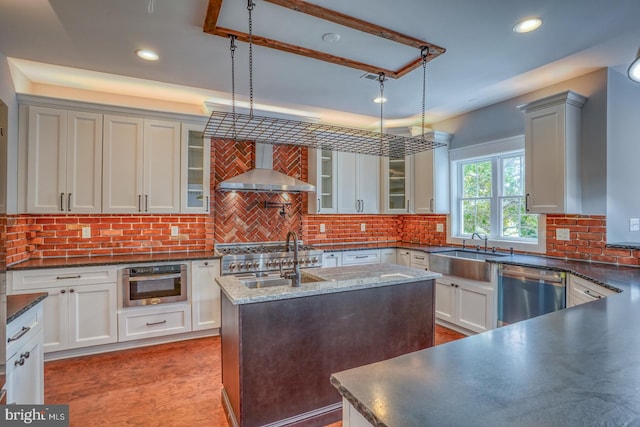 kitchen featuring appliances with stainless steel finishes, pendant lighting, tasteful backsplash, and wall chimney range hood