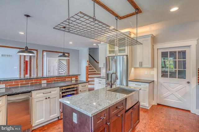 kitchen with dark stone countertops, stainless steel appliances, light hardwood / wood-style flooring, and white cabinetry