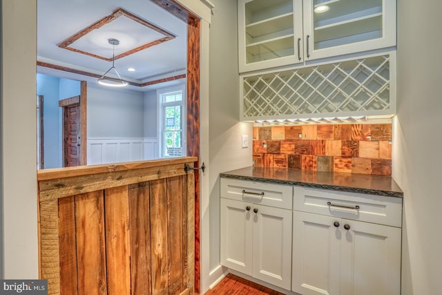 bar featuring white cabinets, dark stone counters, a tray ceiling, and hardwood / wood-style flooring