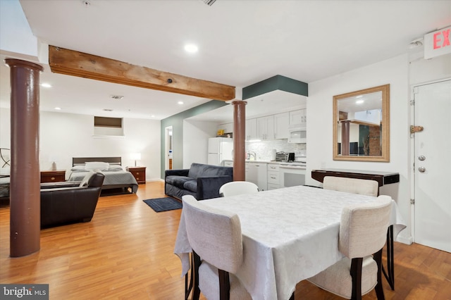 dining room with decorative columns, beamed ceiling, and light hardwood / wood-style floors