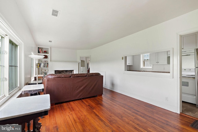 living room with built in shelves and dark wood-type flooring