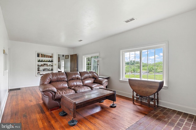 living room with dark wood-type flooring and built in shelves