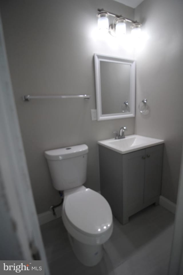 bathroom with toilet, vanity with extensive cabinet space, and tile flooring