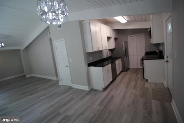 kitchen featuring an inviting chandelier, white cabinets, light wood-type flooring, backsplash, and lofted ceiling with beams