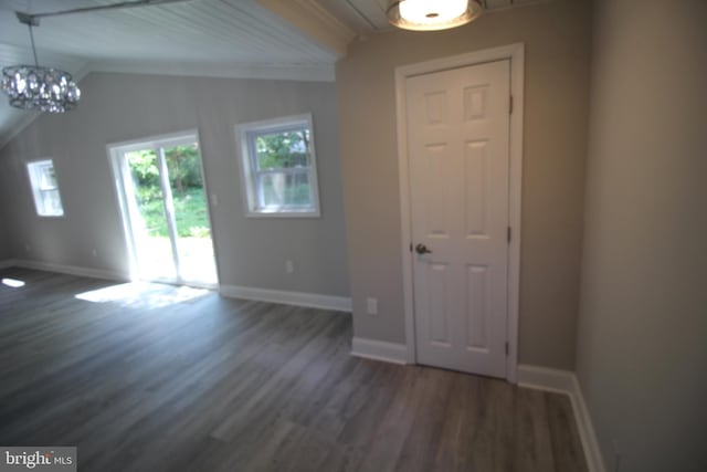 foyer with an inviting chandelier, ornamental molding, and dark hardwood / wood-style floors