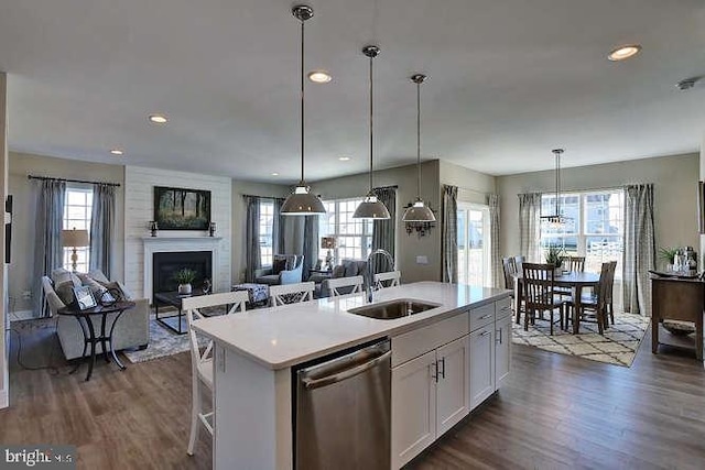 kitchen with sink, white cabinetry, hanging light fixtures, a center island with sink, and stainless steel dishwasher