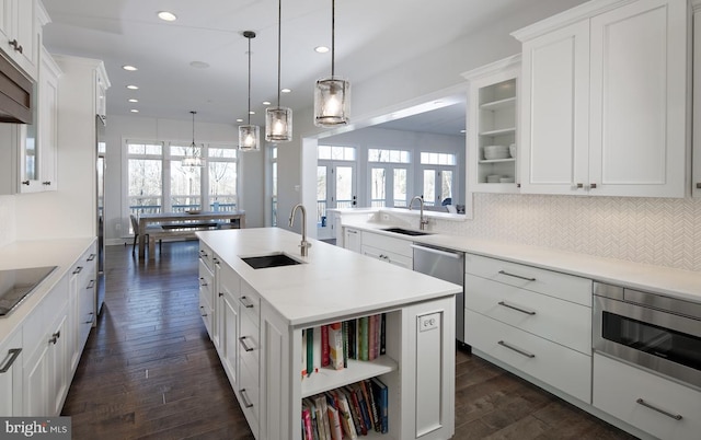 kitchen featuring backsplash, a healthy amount of sunlight, sink, and a center island with sink