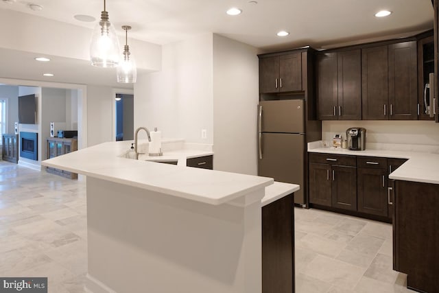 kitchen with dark brown cabinets, light tile patterned floors, appliances with stainless steel finishes, pendant lighting, and sink