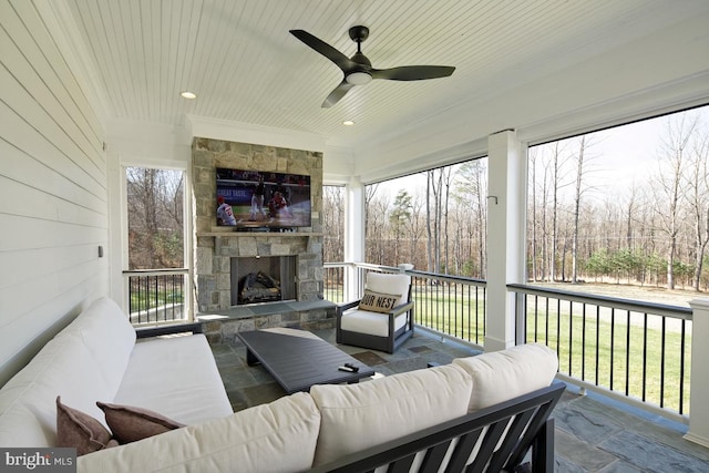 sunroom / solarium with a fireplace, a wealth of natural light, and ceiling fan