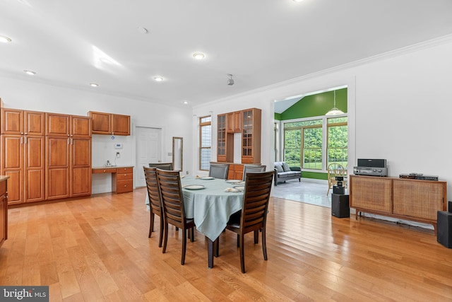 dining area with built in desk, ornamental molding, and light hardwood / wood-style flooring