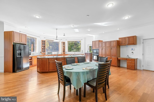 dining area with light hardwood / wood-style floors, ornamental molding, and sink