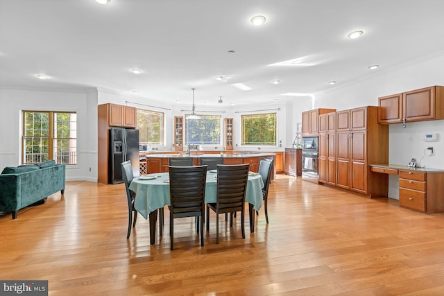 dining space with light hardwood / wood-style floors, ornamental molding, and sink