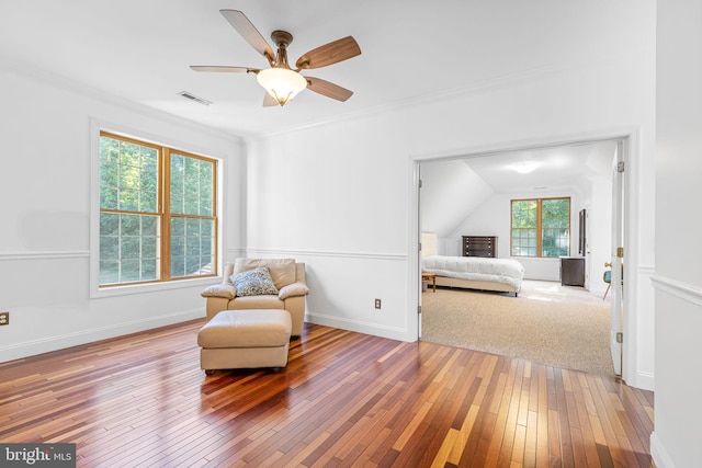 living area featuring ceiling fan, ornamental molding, vaulted ceiling, and hardwood / wood-style flooring