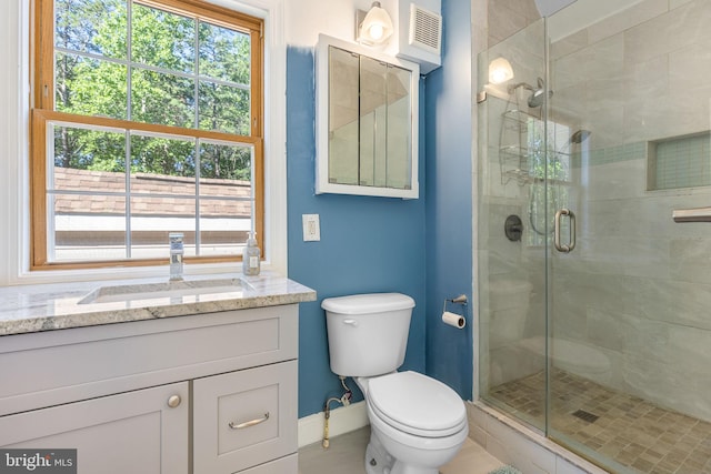 bathroom featuring a shower with door, vanity, and toilet