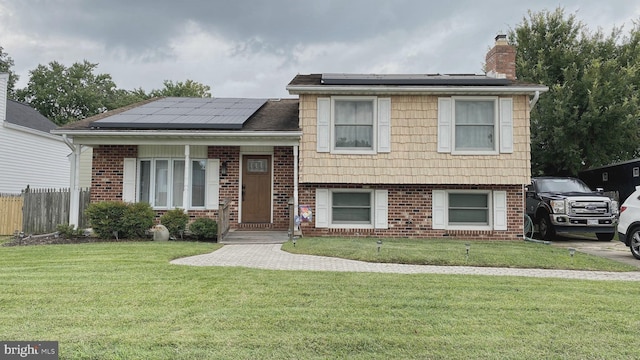 tri-level home with a front yard and solar panels