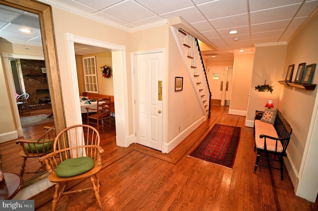 hallway with a drop ceiling, hardwood / wood-style flooring, and ornamental molding