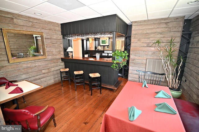 home office featuring a paneled ceiling, wooden walls, indoor bar, and dark hardwood / wood-style floors